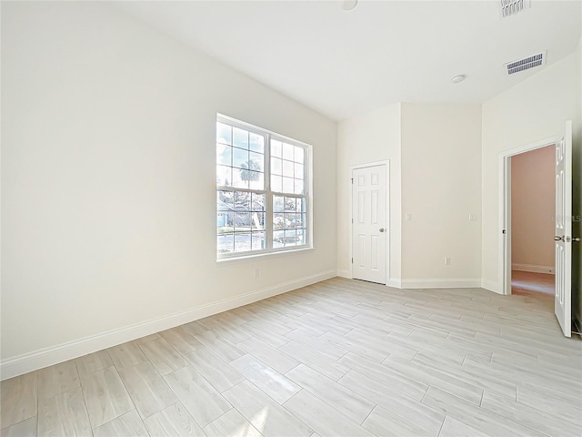 empty room with wood tiled floor, visible vents, and baseboards