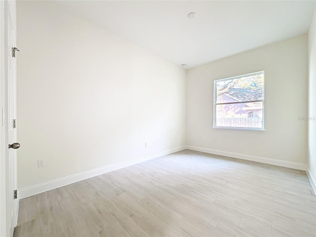 spare room featuring baseboards and light wood finished floors