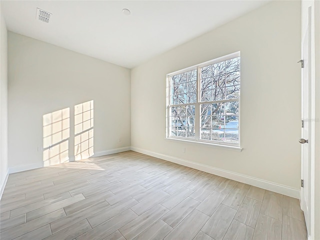 unfurnished room featuring light wood-type flooring, visible vents, and baseboards