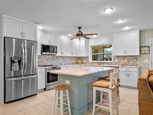 1139 Fairway Dr, Winter Park, FL 32792 - kitchen featuring appliances with stainless steel finishes, a textured ceiling, a kitchen breakfast bar, and tasteful backsplash