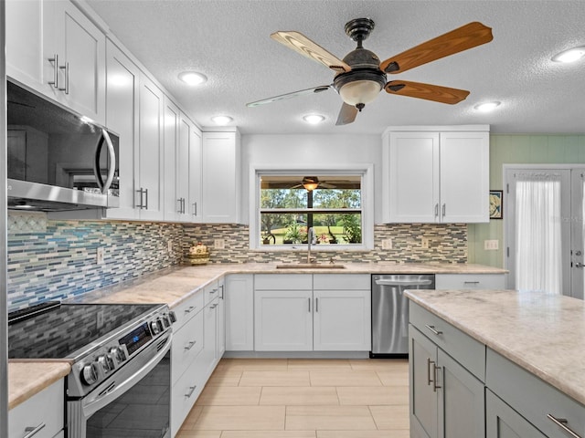 1139 Fairway Dr, Winter Park, FL 32792 - kitchen featuring appliances with stainless steel finishes, a sink, a ceiling fan, decorative backsplash, and white cabinetry