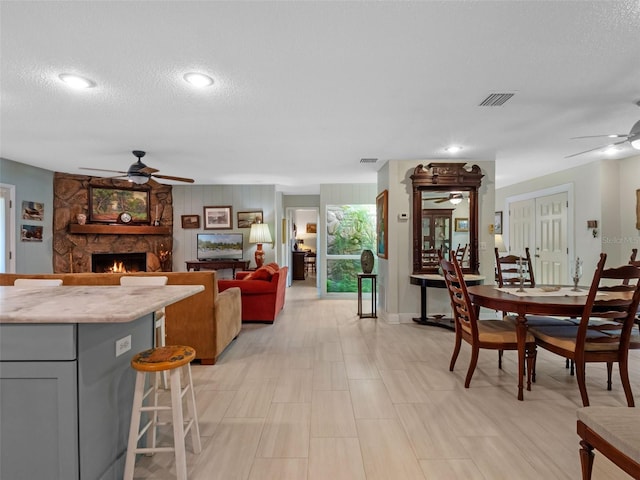 1139 Fairway Dr, Winter Park, FL 32792 - dining area with a ceiling fan, a stone fireplace, a textured ceiling, and baseboards