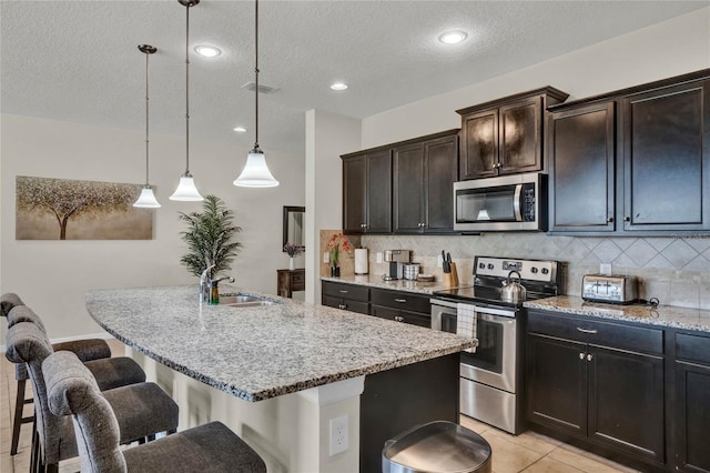 8814 Geneve Ct, Kissimmee, FL 34747 - kitchen featuring a textured ceiling, a sink, a breakfast bar, stainless steel appliances, and light stone countertops