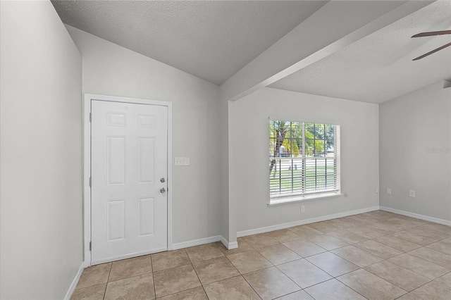 entrance foyer with vaulted ceiling, a textured ceiling, ceiling fan, and light tile patterned flooring