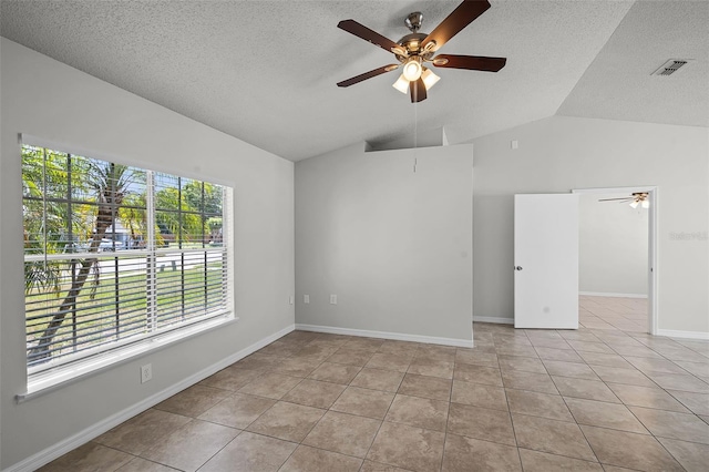 empty room featuring lofted ceiling, tile patterned flooring, visible vents, a ceiling fan, and a textured ceiling