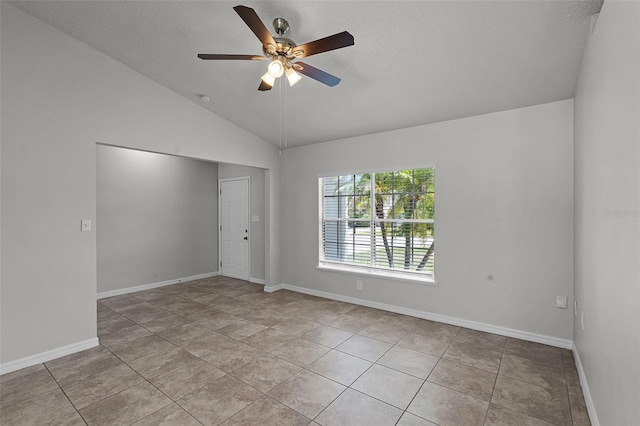 empty room featuring ceiling fan, vaulted ceiling, a textured ceiling, and baseboards