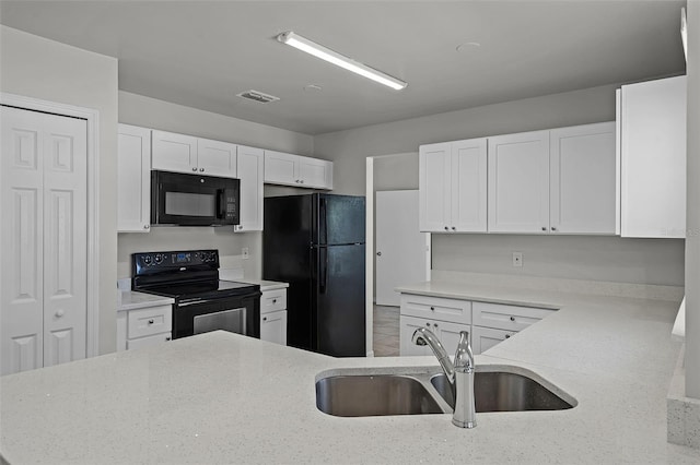 kitchen featuring light stone counters, a sink, black appliances, white cabinetry, and visible vents