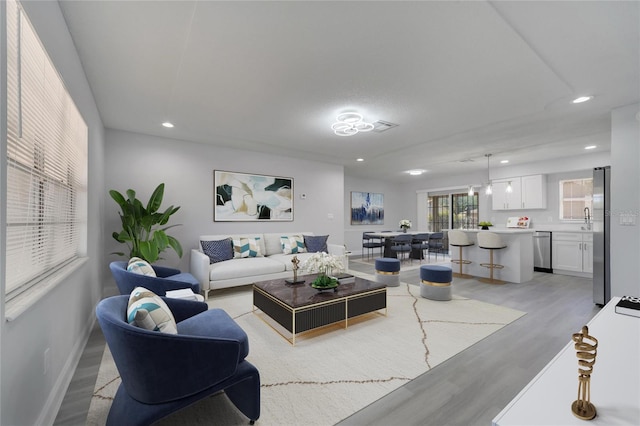 living area featuring baseboards, light wood finished floors, and recessed lighting