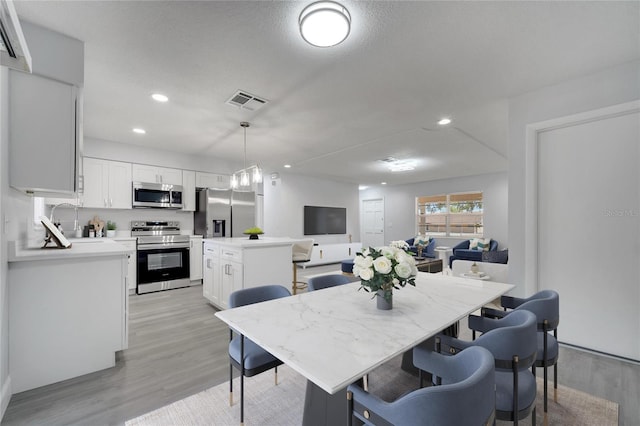 dining area with light wood finished floors, visible vents, and recessed lighting