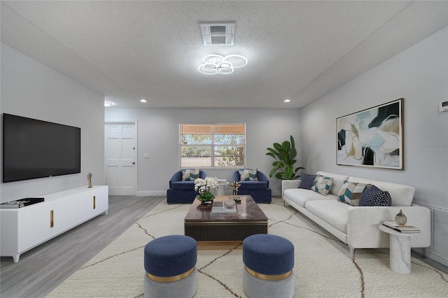 living area with recessed lighting, wood finished floors, visible vents, and a textured ceiling