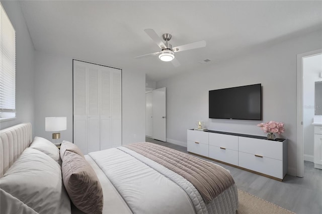 bedroom featuring visible vents, a closet, baseboards, light wood-style flooring, and ceiling fan