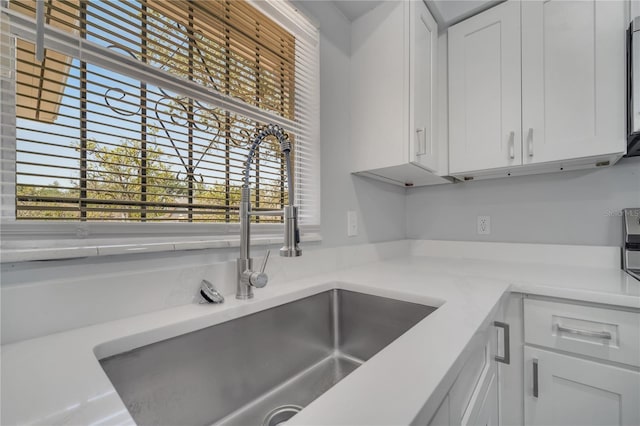 kitchen featuring light countertops, a sink, and white cabinetry