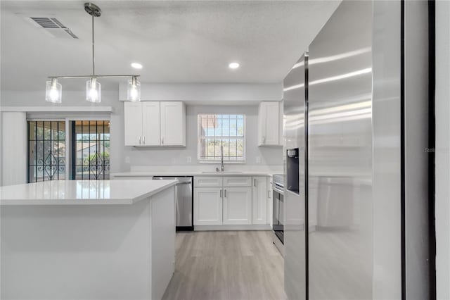 kitchen with white cabinets, a sink, visible vents, light countertops, and appliances with stainless steel finishes