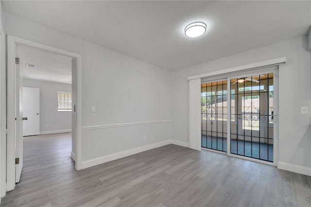 empty room featuring baseboards, a ceiling fan, and wood finished floors