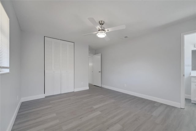 unfurnished bedroom with light wood-style flooring, visible vents, baseboards, a ceiling fan, and a closet
