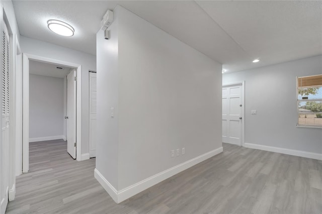 corridor with recessed lighting, light wood-style floors, and baseboards