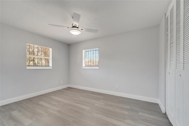 unfurnished bedroom featuring wood finished floors, a closet, a ceiling fan, and baseboards