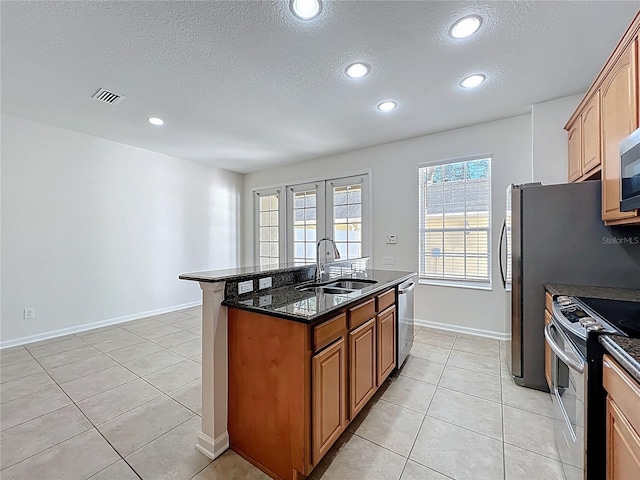 kitchen with visible vents, a sink, a center island with sink, a textured ceiling, and appliances with stainless steel finishes