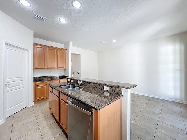 kitchen with stainless steel dishwasher, a sink, dark stone countertops, visible vents, and light tile patterned floors