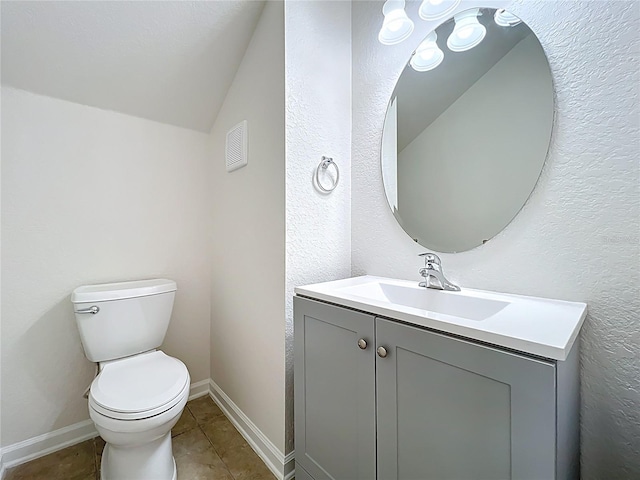 bathroom with tile patterned floors, toilet, vaulted ceiling, baseboards, and vanity