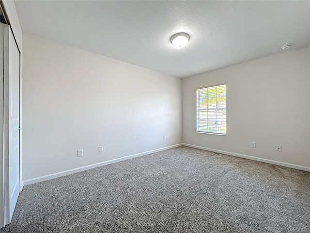 carpeted empty room with baseboards
