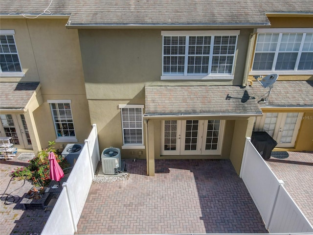 rear view of property featuring french doors, central AC, and stucco siding