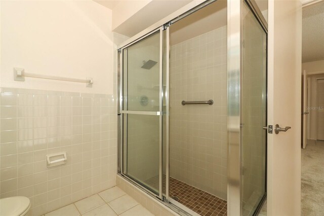 406 Red Coat Ln, Orlando, FL 32825 - full bathroom with tile walls, a stall shower, tile patterned flooring, toilet, and a wainscoted wall