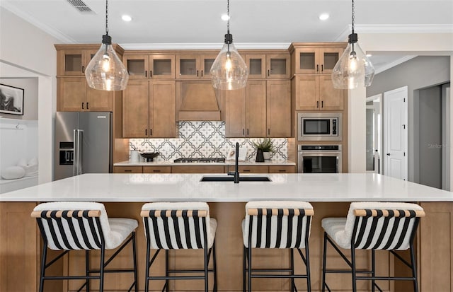 kitchen featuring stainless steel appliances, custom exhaust hood, a sink, and brown cabinetry