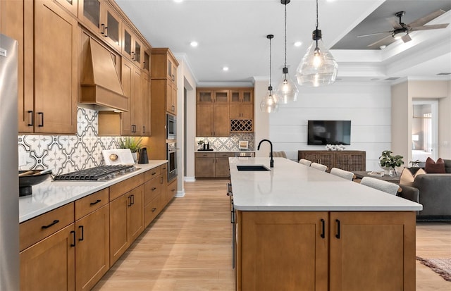 kitchen featuring a sink, open floor plan, custom range hood, crown molding, and appliances with stainless steel finishes