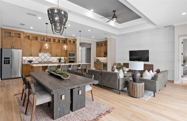 dining area featuring light wood-type flooring, visible vents, crown molding, and ceiling fan