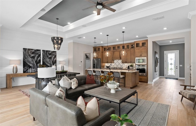 living room with baseboards, visible vents, recessed lighting, light wood-style floors, and ceiling fan with notable chandelier