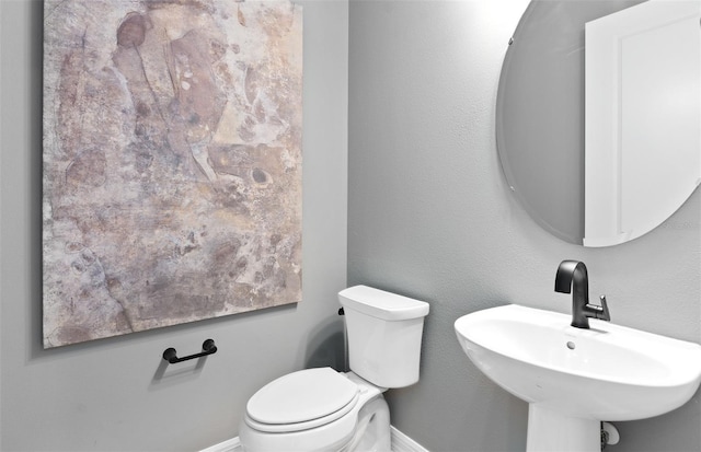 bathroom featuring toilet, a sink, and baseboards