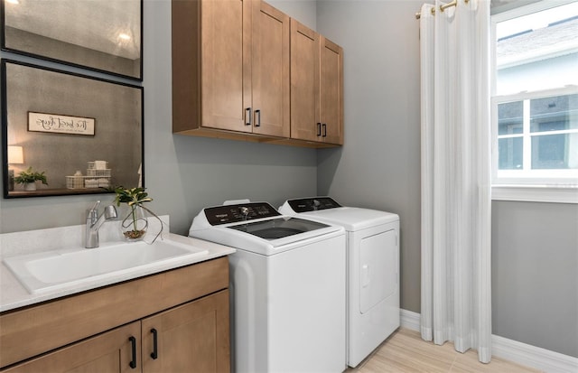 laundry area featuring washing machine and clothes dryer, cabinet space, a sink, and baseboards