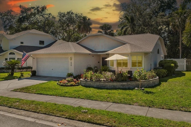 ranch-style house with a garage, driveway, a front yard, and fence