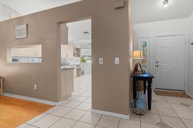 foyer with baseboards, visible vents, and light tile patterned floors