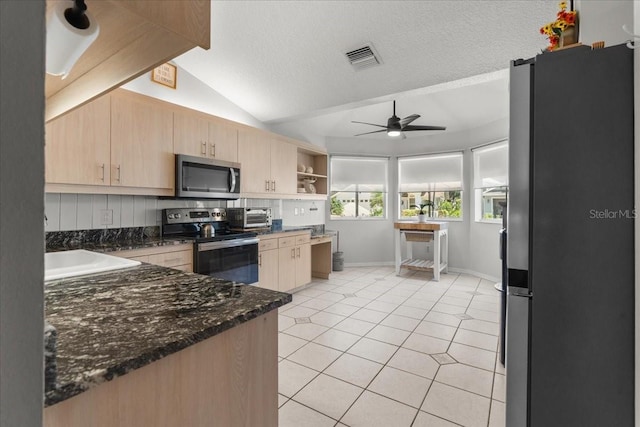 kitchen with light brown cabinetry, visible vents, lofted ceiling, a ceiling fan, and appliances with stainless steel finishes