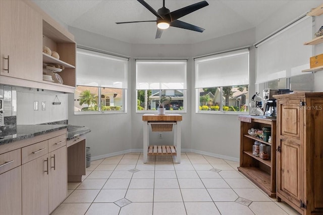 kitchen featuring dark stone countertops, open shelves, light tile patterned flooring, baseboards, and ceiling fan
