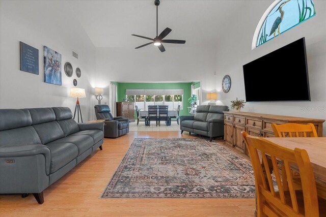 living room with high vaulted ceiling, a ceiling fan, wood finished floors, and visible vents