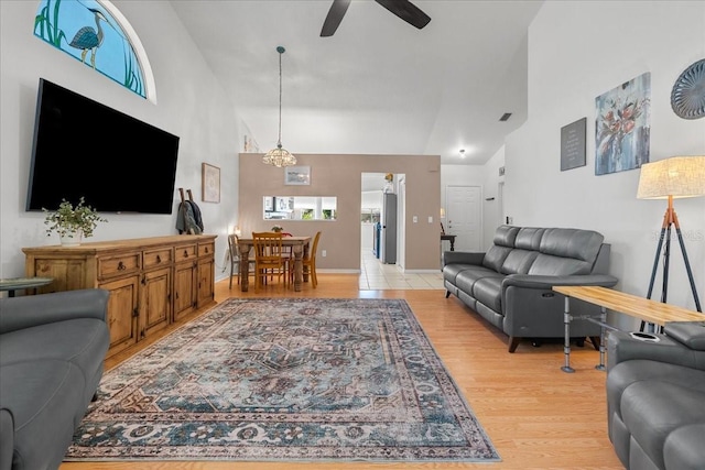 living room with high vaulted ceiling, ceiling fan, and light wood-style flooring