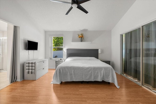 bedroom featuring light wood-type flooring, a textured ceiling, lofted ceiling, and ceiling fan