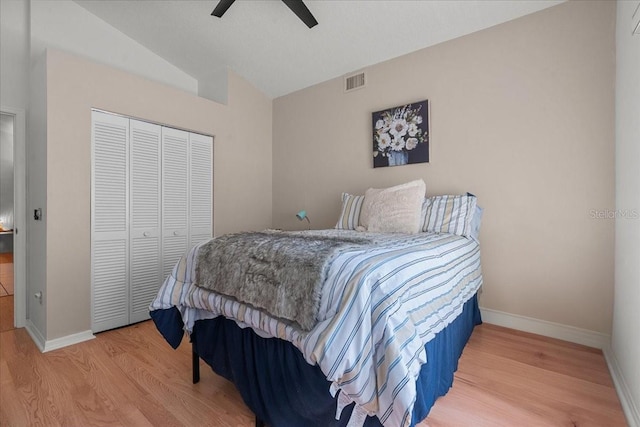 bedroom with baseboards, lofted ceiling, wood finished floors, and a closet