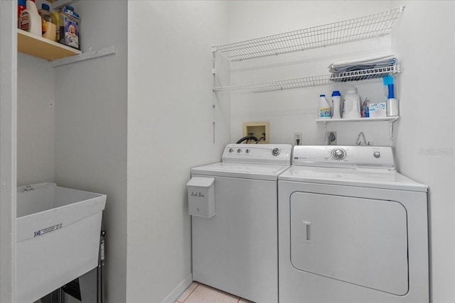 laundry room featuring a sink, light tile patterned flooring, washer and dryer, baseboards, and laundry area