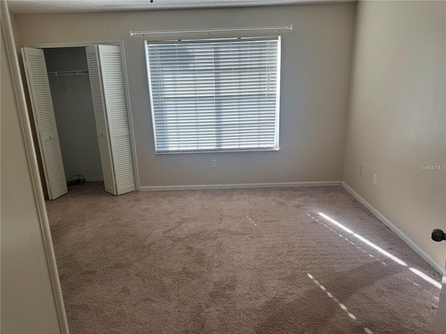 unfurnished bedroom featuring baseboards, carpet floors, and a closet