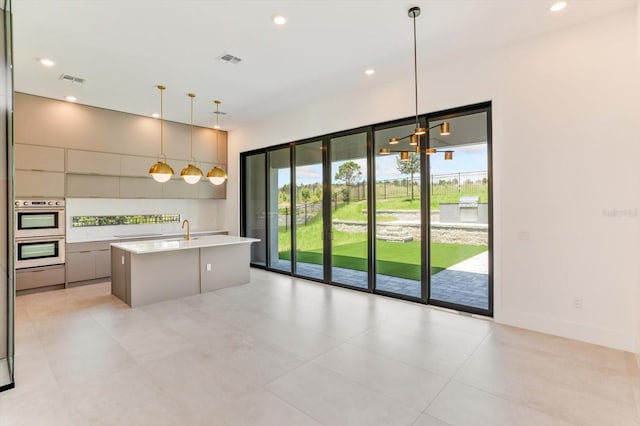 16825 Bolsena Dr, Montverde, FL 34756 - kitchen featuring double oven, light countertops, modern cabinets, hanging light fixtures, and a kitchen island with sink