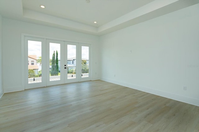16825 Bolsena Dr, Montverde, FL 34756 - empty room with a tray ceiling, light wood-style floors, french doors, and recessed lighting
