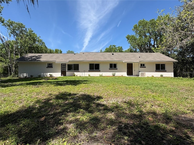back of house with stucco siding, a yard, and central AC