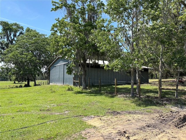 view of yard with an outdoor structure, a pole building, and fence