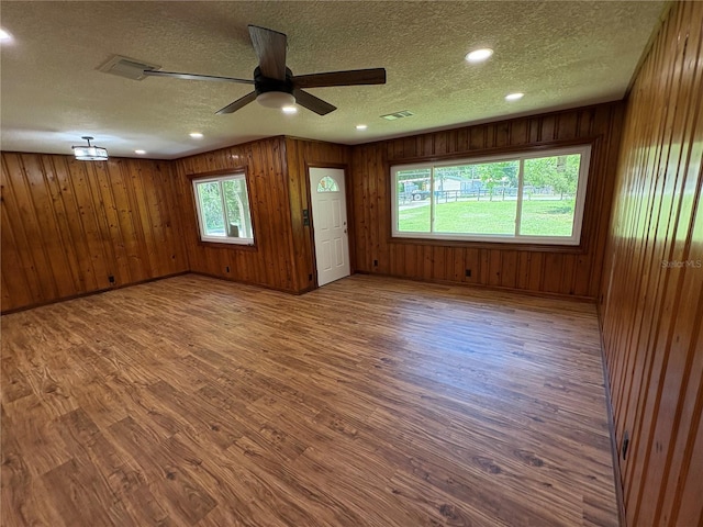 empty room featuring a ceiling fan, wood finished floors, a textured ceiling, visible vents, and recessed lighting