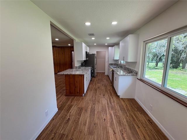 kitchen with baseboards, light stone counters, a sink, and visible vents