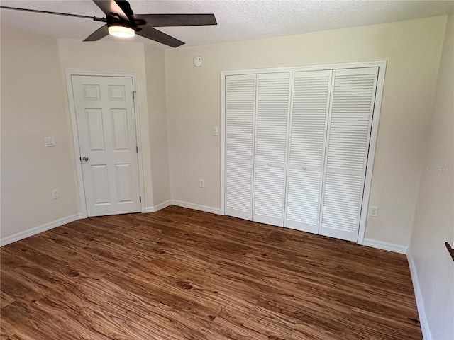 unfurnished bedroom with dark wood-type flooring, a closet, and baseboards